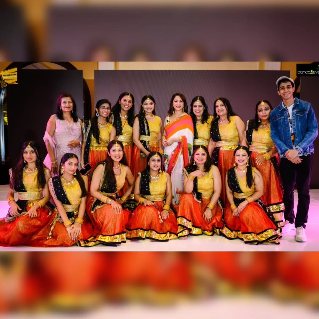 Dance4Ever adult dancers in gold and orange with Madhuri Dixit