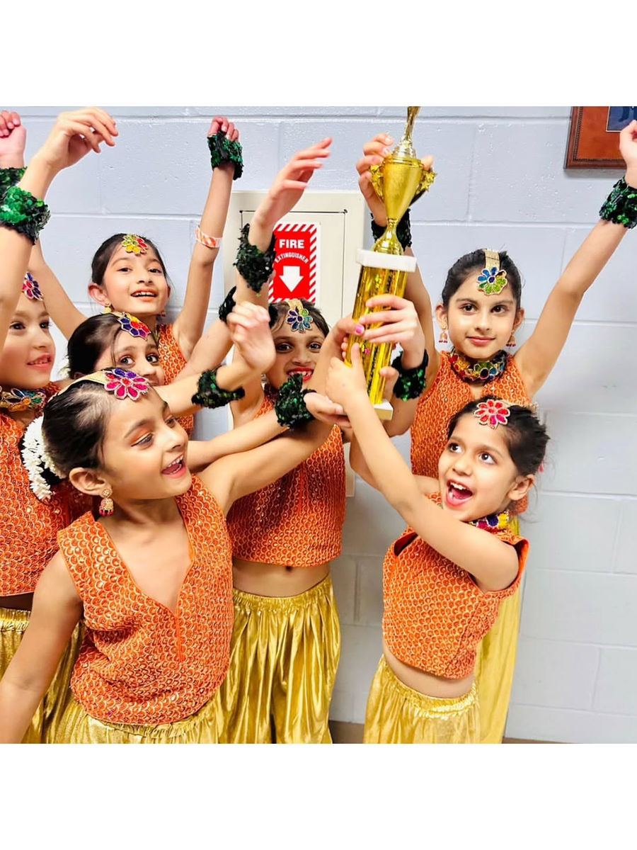 Young dancers cheering with a trophy backstage