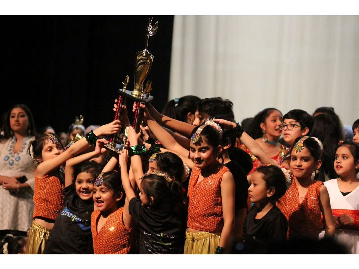 Dance4Ever kids lifting a trophy together on stage