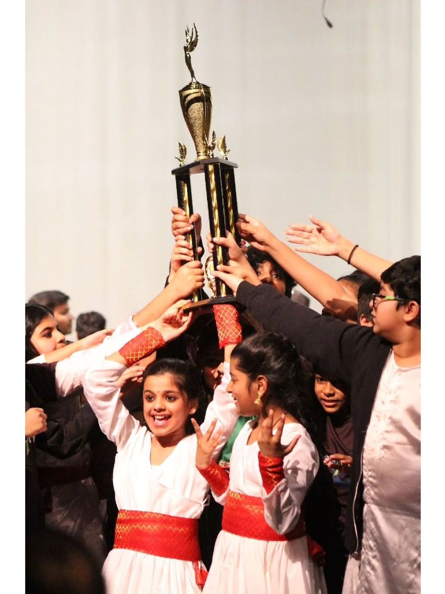 Kids in white costumes holding a trophy high