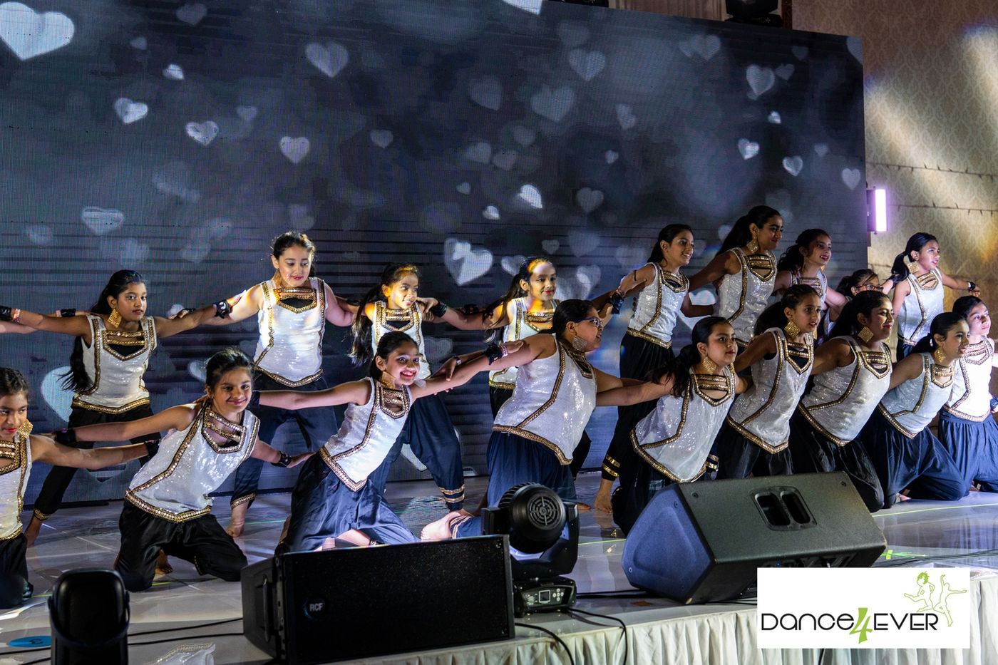 A large teen ensemble mid routine on stage