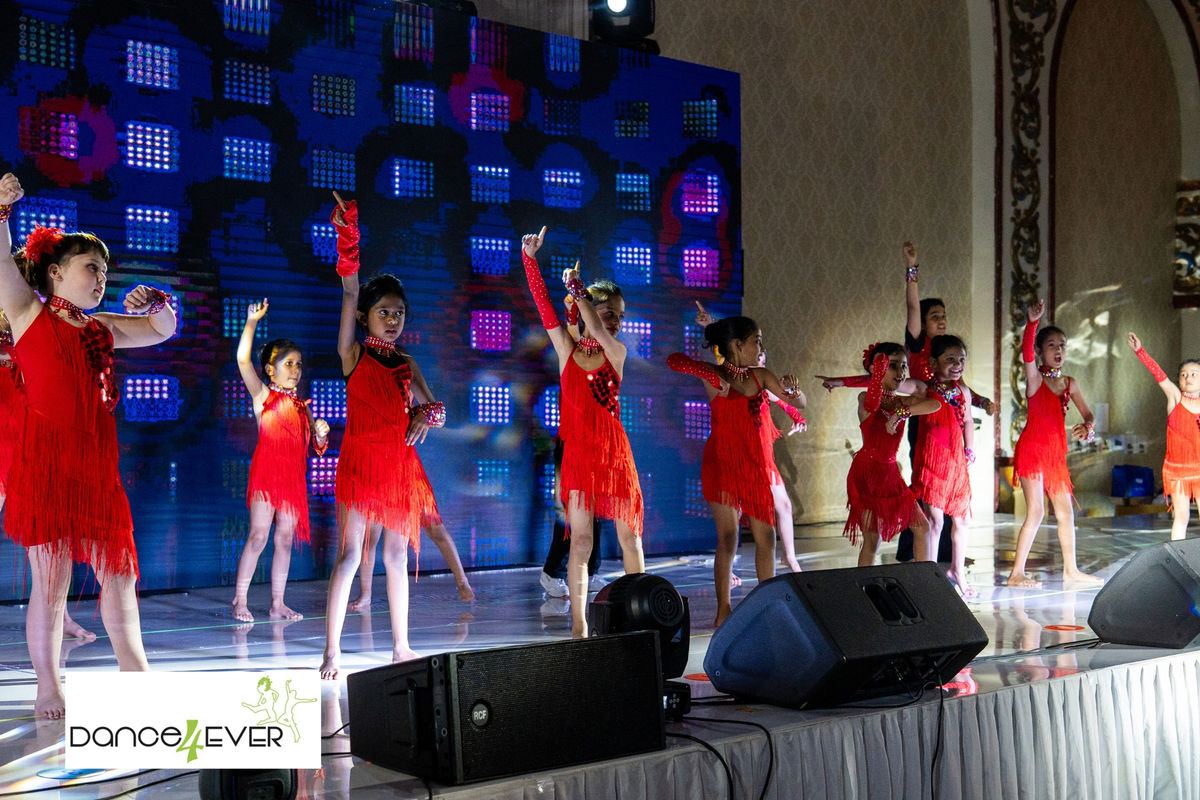Young students in red fringe costumes performing on stage