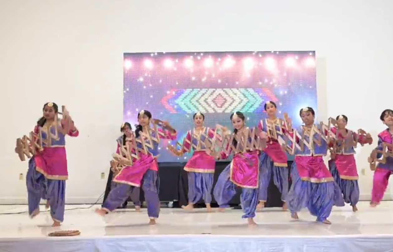 Dance4Ever dancers in pink and blue Bhangra costumes with saaps on stage