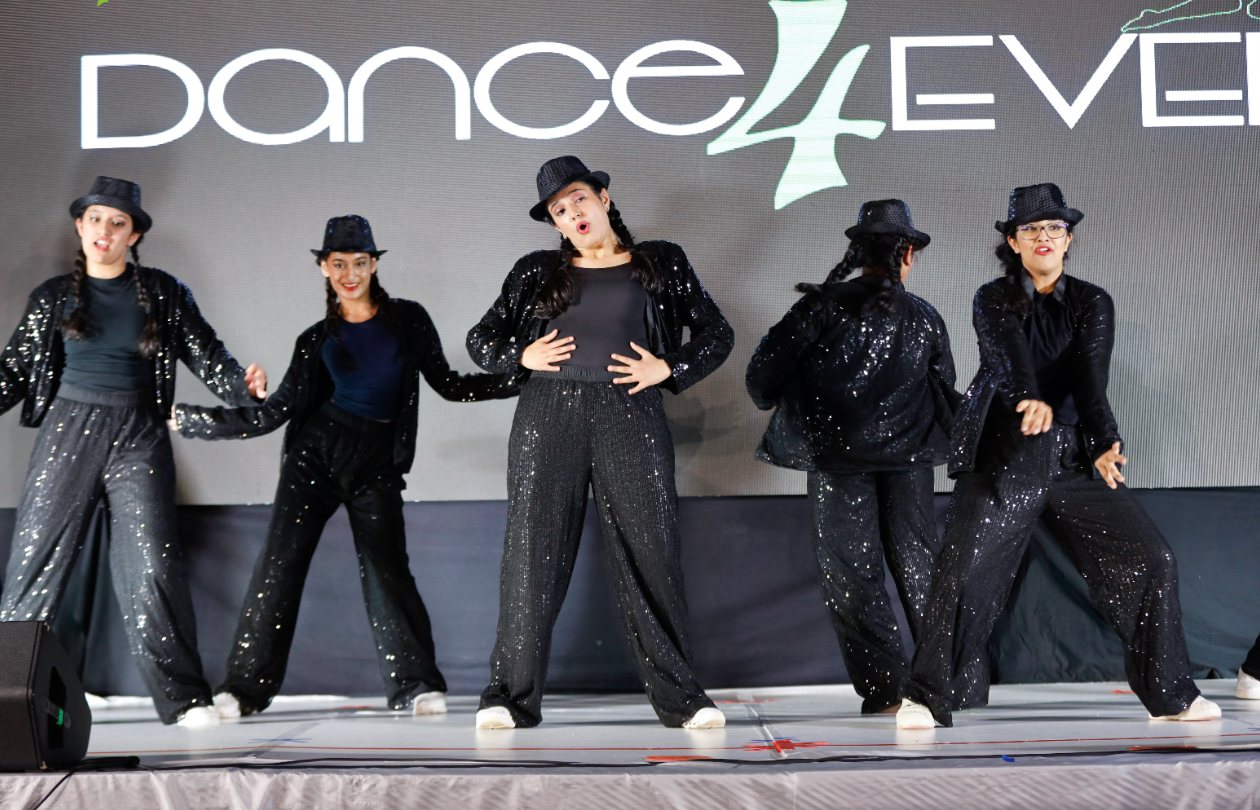 Three dancers in white and silver holding a jazz pose on stage